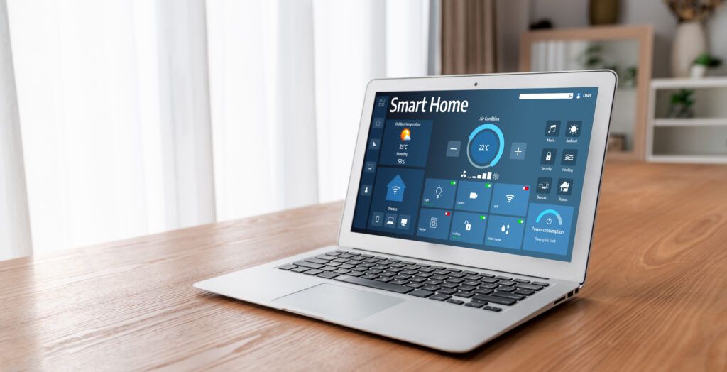 ordenador portátil sobre mesa de madera mostrando un panel de control de Smart Home para gestionar la temperatura y el consumo energético.