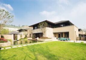 modern building by the fishpond and beautiful meadow in blue sky