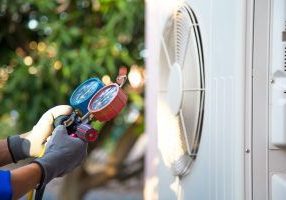 Mechanic air conditioner technician using manifold gauge checking refrigerant for filling home air conditioning and air duct cleaning and maintenance outdoor compressor unit.